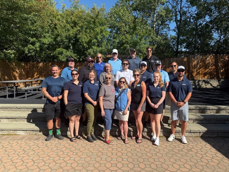 Group photo of about twenty people in golf shirts and caps on outdoor stone steps at the 2026 Far From Par Charity Golf Tournament.