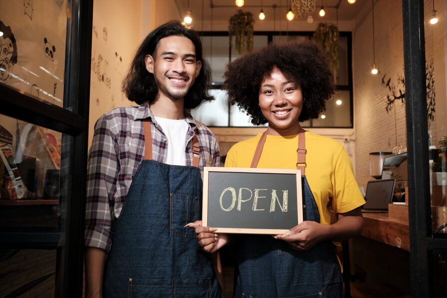 Young couple hold sign: open for business